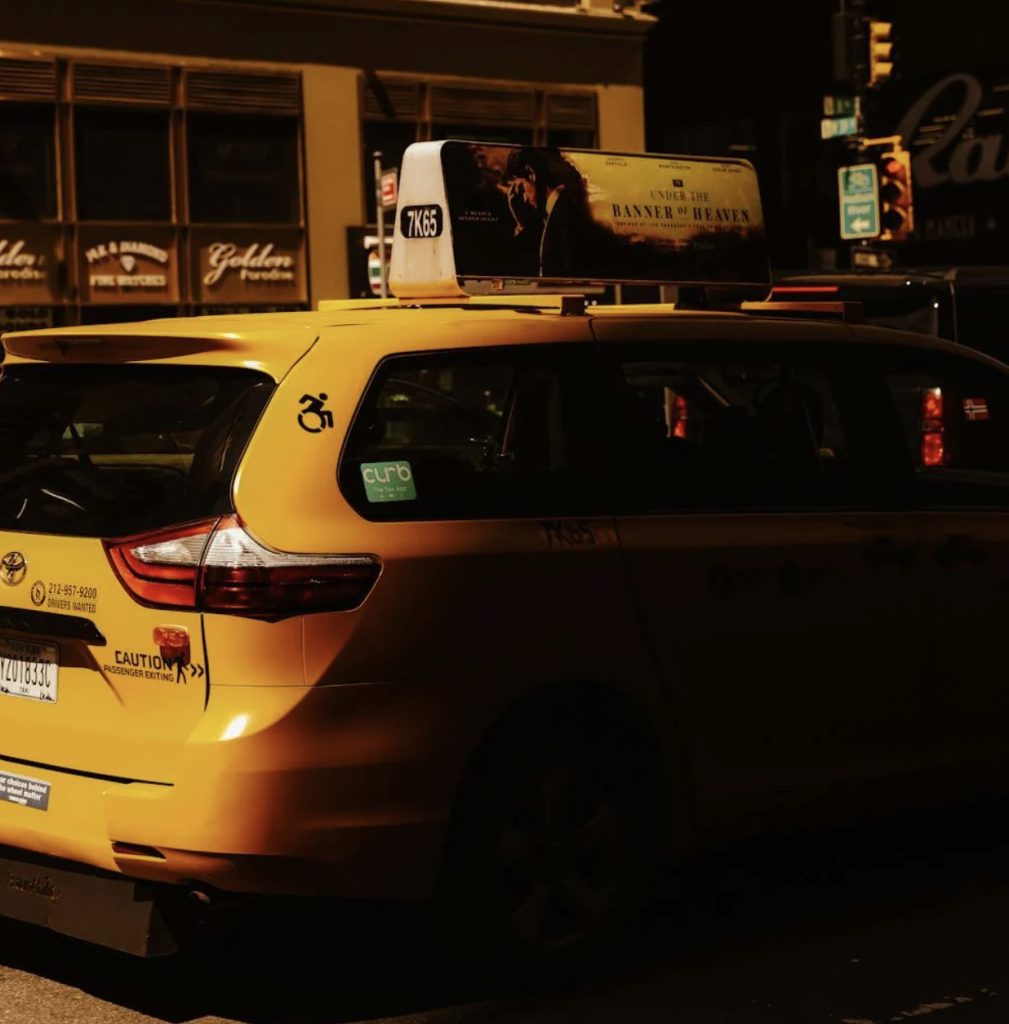 Mini van taxi obscured in shadow with taxi ad on top